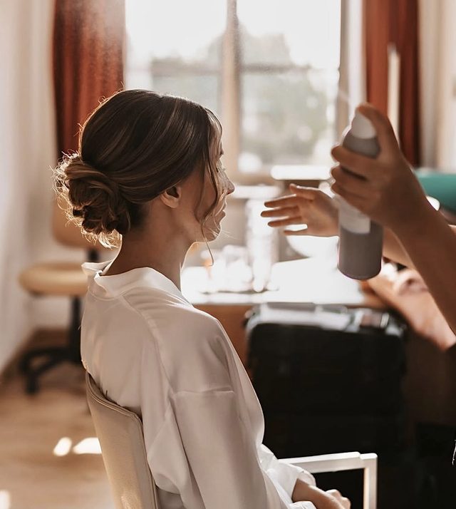 Bruid met lage chignon bij het raam