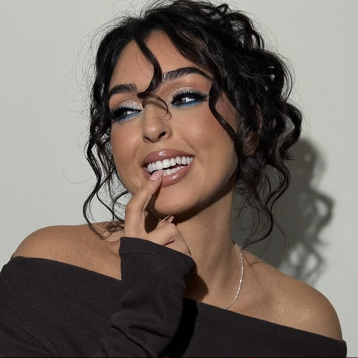 Glanzende make-up met blauwe eyeliner en losse krullen